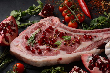 Fresh Raw Beef bone rib steak on black board with herbs and spices