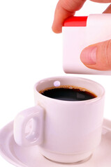 Mettre de l'aspartame dans une tasse de café en gros plan sur fond blanc