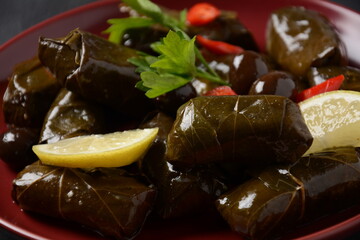 Traditional Greek cuisine. Wrapped rice in grape leaves. Dolma with lemon, spices, various pickled olives and hot peppers.