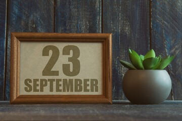 september 23rd. Day 23 of month, date in frame next to succulent on wooden background autumn month,...