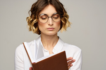 woman with notepad in hands business work beige background glasses hairstyle