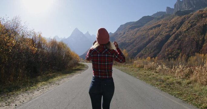 Young woman walking in the autumnal mountains. Mountain and happy tourist