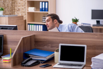 Young male employee in industrial espionage concept