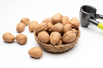 Walnuts in basket on white background next to nutcracker