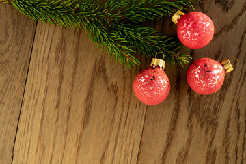 Christmas decoration, a branch of fir tree with three pink baubles on rustic wooden background. Holiday time theme for Christmas and New Year