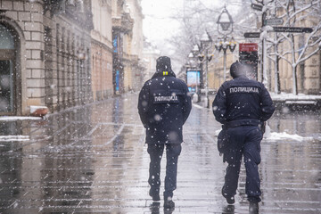 Police patrolling and walking trough empty streets on snowy day in Belgrade,Serbia during police...