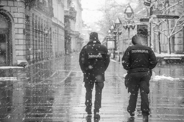 Police patrolling and walking trough empty streets on snowy day in Belgrade,Serbia during police...