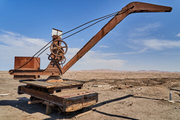 old crane on rails on an abandoned saltpeter mining town in the Atacama desert of Chile, South America