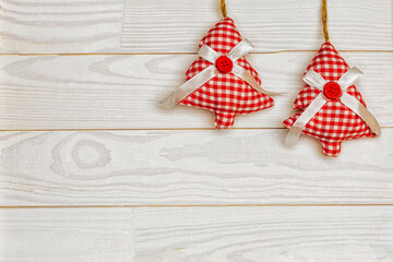 Christmas or New Year decoration background with hanging red Christmas trees on a white wooden table with copy space.