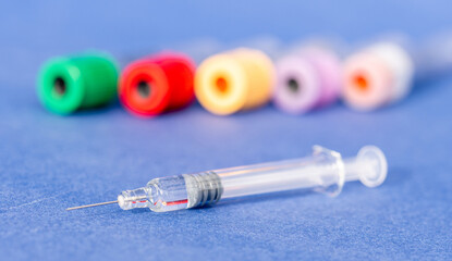 Vaccine - injection of a vaccine with a syringe - solution against the Covid-19 coronavirus - close-up on a syringe and a hand with tubes in the background