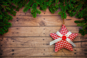 Christmas or New Year decoration background with hanging red star in pine branches on a wooden table with copy space.