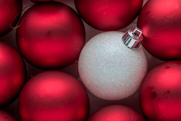 to be original during christmas period.
a  white Christmas Decoration Balls stands out from a group of red balls. originality. horizontal composition