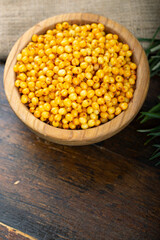 Sea buckthorn. Fresh ripe berry in wooden bowl with leaves on wood background.