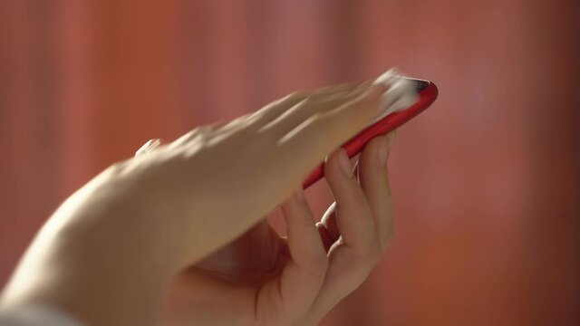 Close-up of woman hand using wet wipe and sanitizer to clean cell phone screen. People cleaning and disinfecting mobile telephone monitor to kill virus and germs. Female hands holding smartphone