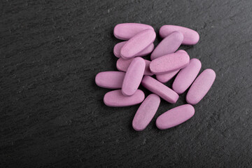 Obraz na płótnie Canvas Pink pills on a black background. Health care concept. Space for text. Conservative medicine.