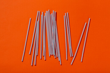 Colored tubules for juice and cocktails on orange background. Space for text.