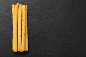 Homemade Italian Grissini Breadsticks on a black background. Traditional italian snack with herbs.  Space for text.
