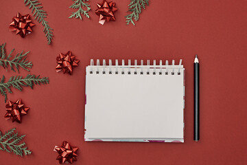 New Year's decor and a notebook in the center on a red background. Christmas decoration. Copy space, flat lay, mock up, top view