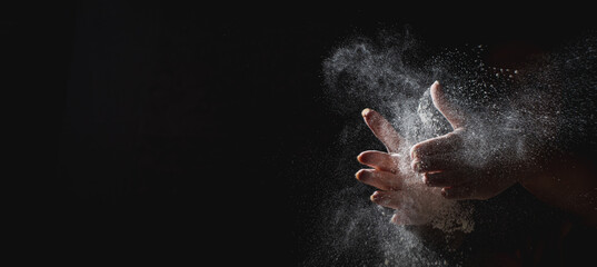 woman chef hand clap with splash of white flour and black background with copy space.