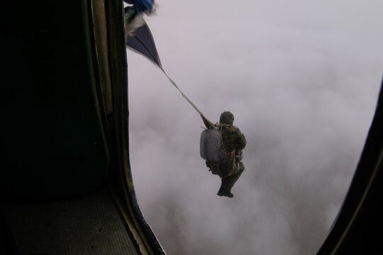 A paratrooper has just jumped out of a plane into the cloudy sky.