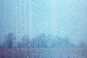 raindrops on glass, view through the window landscape autumn forest, park