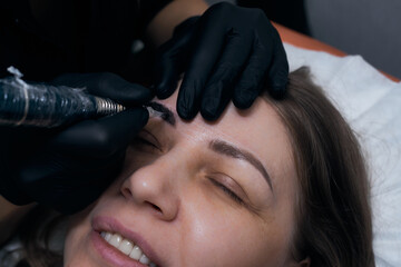 Permanent eyebrow makeup procedure. Eyebrow tattooing, process. The use of tools by a master for permanent eyebrow makeup.