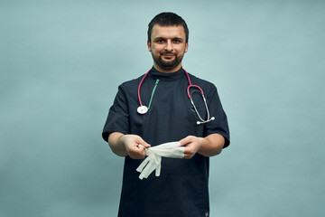 A doctor in professional clothing takes off protective gloves. Personal protective equipment against the virus.