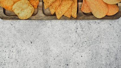 Potato and corn chips on a dark wooden stand and sauces, the finished dish. Junk food.