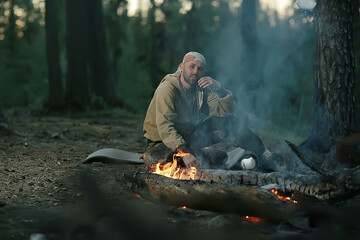 tourist bonfire huntsman, a man in the taiga basking in the fire