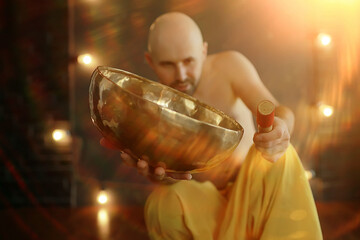 Tibetan singing bowl, a monk in yellow pants meditates and plays the musical bowl, Buddhism, religion