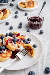 High angle view of cottage cheese pancakes with sour cream, blueberry jam and blueberries