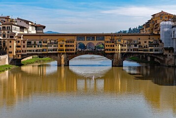 Obraz premium The Ponte Vecchio at Florence reflecting at the Arno River, Tuscany Region in Italy 
