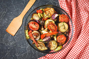 Roasted vegetables mix on plate on black stone background