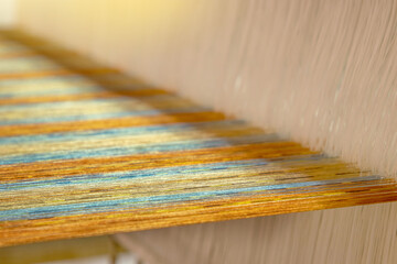 closeup of multicolour yarn on loom, abstract fabric weaving background