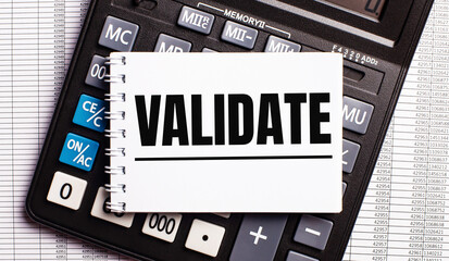 On the table are reports, a calculator and a card with the word VALIDATE on it. Business concept