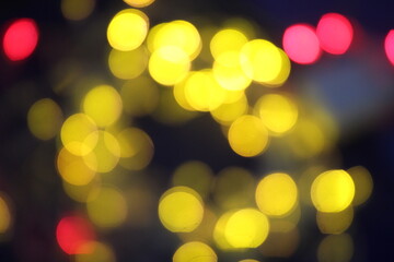 Bright, multicolored bokeh lights of Christmas garland on a black background, texture of new years lights for design.