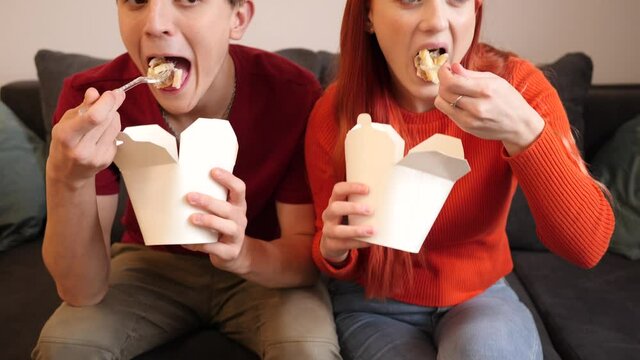 Young couple stay at home eat dober kebab takeaway boxes from food delivery watching tv