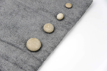 Fototapeta na wymiar Gray zen pebble hot stones with towel on massage table in beauty salon. Hot stone massage setting. Concept set of harmony, balance and meditation, spa, relax, spa treatment