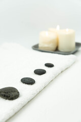 Fototapeta na wymiar Gray zen pebble hot stones with towel on massage table in beauty salon. Hot stone massage setting. Concept set of harmony, balance and meditation, spa, relax, spa treatment