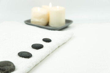 Obraz na płótnie Canvas Gray zen pebble hot stones with towel on massage table in beauty salon. Hot stone massage setting. Concept set of harmony, balance and meditation, spa, relax, spa treatment