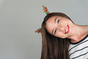 A happy young woman with Christmas decoration in her hair looks into the camera. Celebrating Christmas and New Year