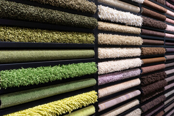 Samples of carpets of different colors on a stand in a store or production. Multi-colored carpet samples on the floor