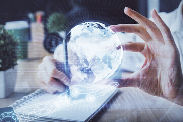 Double exposure of hands making notes with world map hologram and data theme icons. Concept of global computer data.