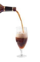 Dark craft beer pouring from bottle into glass with stem. Alcohol craft drink splash