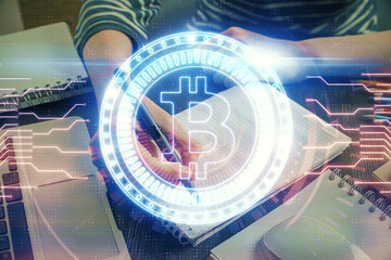 Cryptocurrency hologram, bitcoin, ico theme over hands taking notes background. Concept of...