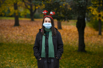 Girl with protective mask and Christmas decoration on her head in nature