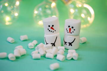 marshmallow snowman on mint turquoise background with garland lighting