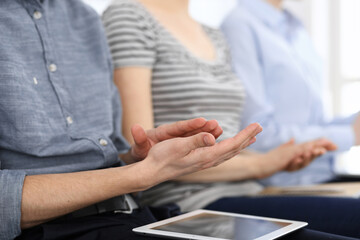 Business people clapping at meeting or conference, close-up of hands. Group of unknown businessmen and women in modern white office. Success teamwork, corporate coaching and applause concept