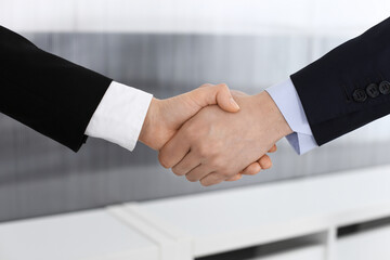 Businessman and woman shaking hands in office. Concept of handshake as success symbol in business