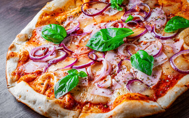 Pizza with Mozzarella cheese, ham, tomato sauce, onion, pepper, Spices and Fresh basil. Italian pizza on wooden table background
